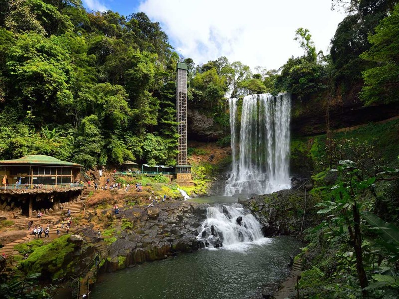 Dambri Waterfall plunging dramatically into a misty pool.