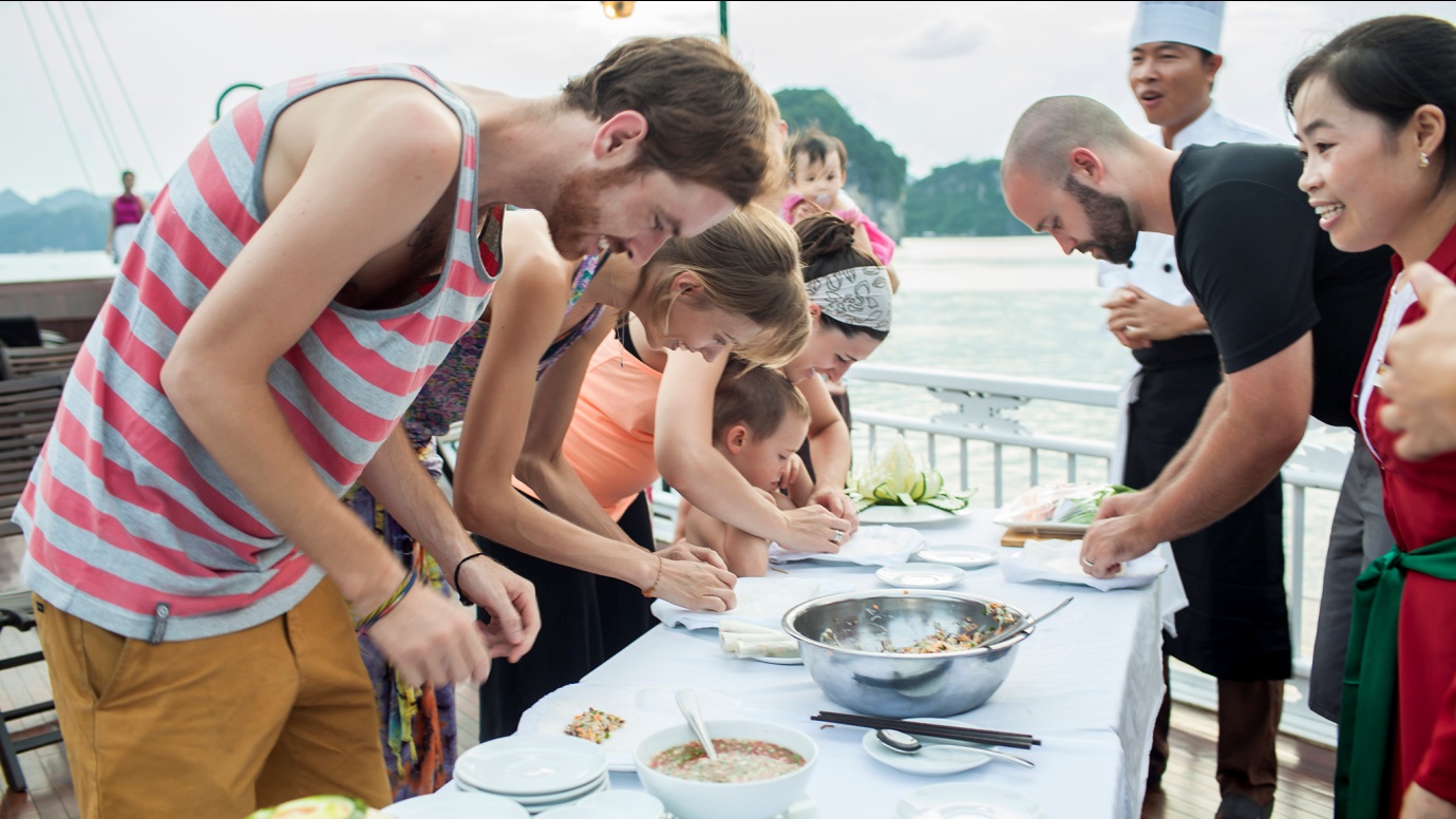 Cruise passengers learning to prepare fresh spring rolls during a cooking class