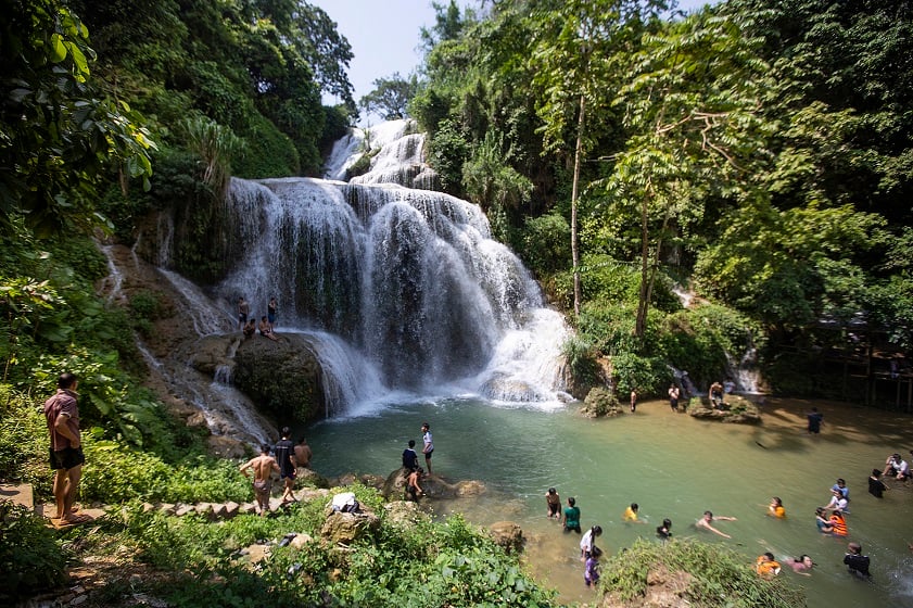 Visitors admiring the jade‑green pool at the foot of Mu Waterfall.