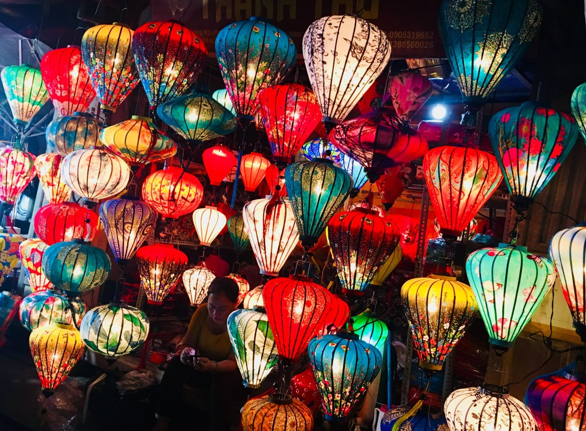 Colorful Hoi An lanterns and a traditional conical hat, representing the iconic symbols of Vietnam.