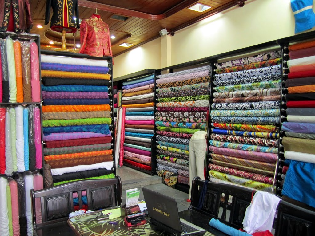 A colorful display of silk fabrics in a Hoi An tailor shop, ready to be transformed into custom garments.